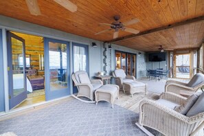 A covered outdoor area with wicker furniture, a ceiling fan, and a television mounted on the wall.