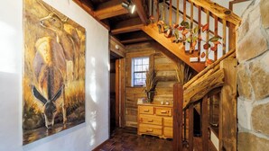 Una escalera de madera de diseño rústico, una pared de piedra y un cuadro con canguros en la pared.