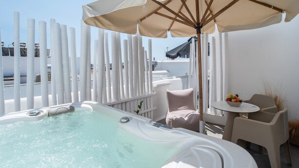 A rooftop terrace with a hot tub, outdoor seating, and a view of the sea.