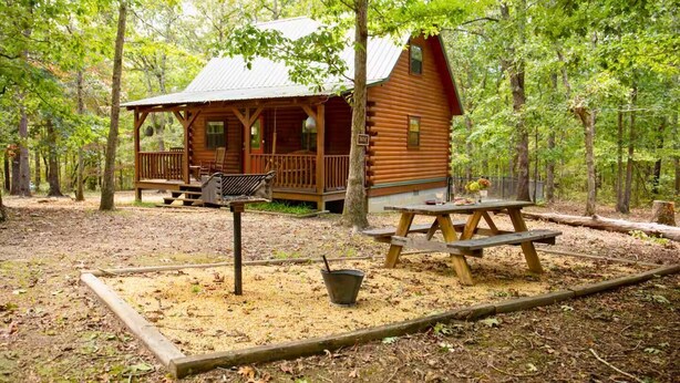 A rustic cabin with a porch, picnic table, and a bird feeder.