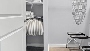 A modern closet with shelves, a hanging rack, and a striped towel. - Nice 1BR Near Encore Boston tl51 (Everett)