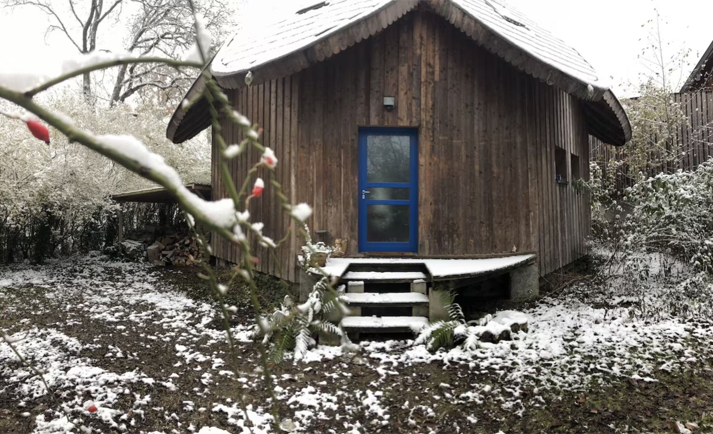 A wooden cabin with a blue door, a small porch, and steps leading up to the entrance.
