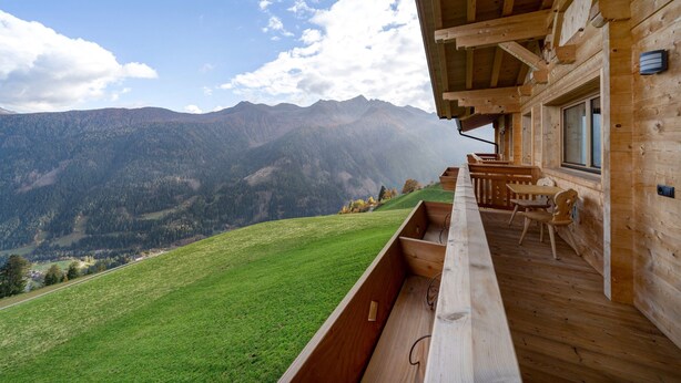 Una cabaña de madera con un balcón que da a un paisaje montañoso.