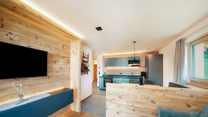 Una sala de estar moderna con un muro de acento de madera, un televisor de pantalla plana, un banco empotrado y un sofá.