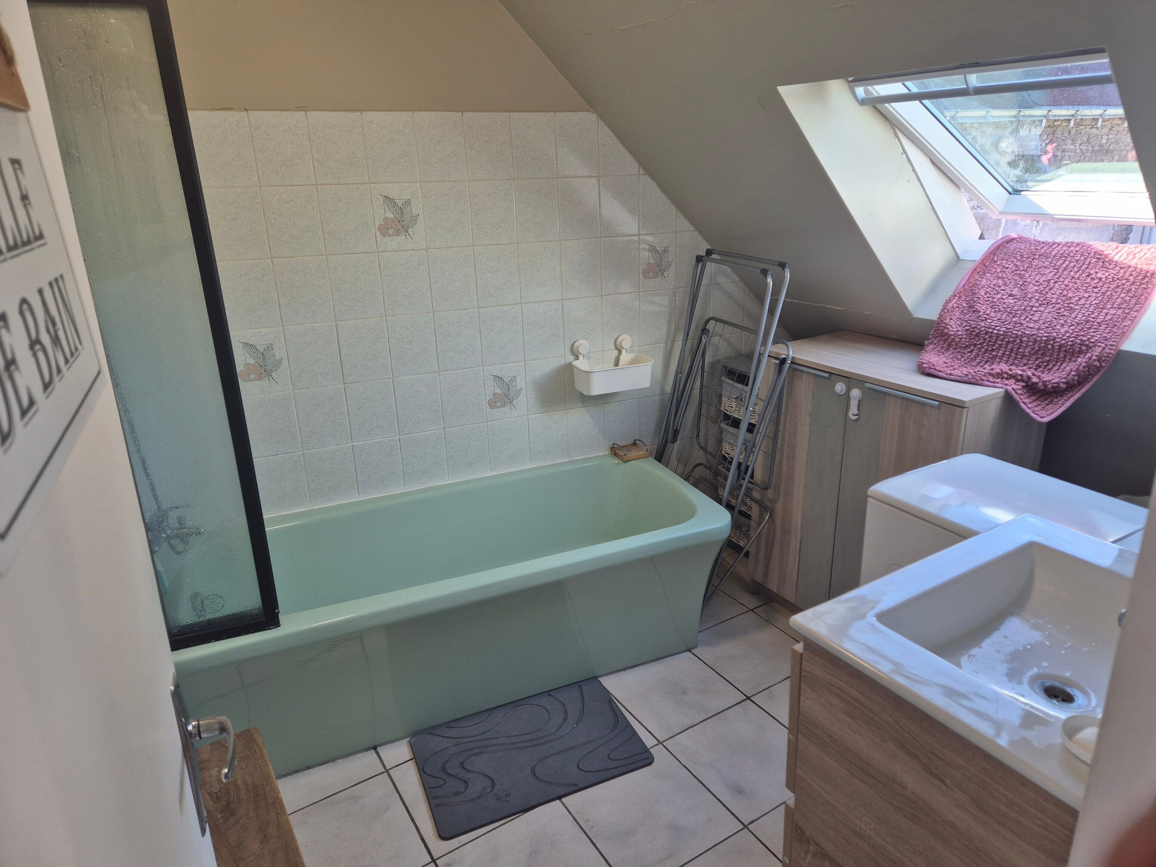 A bathroom with a bathtub, a window, and a towel rack.