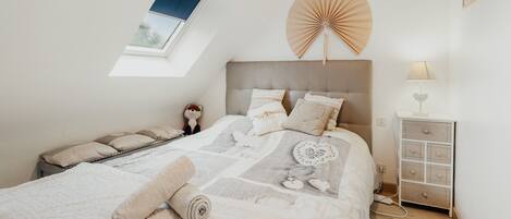 A bedroom with a bed, a bedside table, a lamp, a fan, and a window.