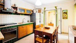 Een keuken met houten kastjes, een fornuis en een eettafel met stoelen.