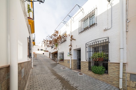 A narrow cobblestone street flanked by buildings with barred windows and potted plants.. Country House 'Los Perez Alojamiento Rural' with Shared Terrace, Wi-Fi and Air Conditioning