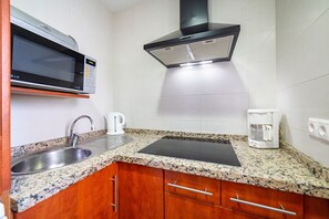 A kitchen with a microwave, coffee maker, and a black induction cooktop.
