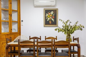 A dining area with a wooden table, chairs, a glass cabinet, and a painting on the wall.