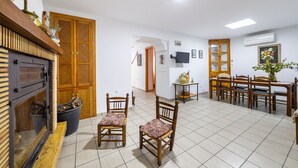 Un comedor con sillas de madera y una mesa, una chimenea con protector y un piso de baldosas.