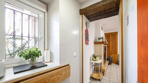 Un baño con ventana, una planta, un perchero para toallas y un banco de madera.