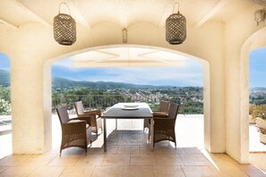 An outdoor patio with a table and chairs, a view of the landscape, and two hanging lanterns. - Holiday Home 'Casa Vista Del Mar' with Sea View, Private Pool and Wi-Fi (Calonge)