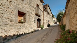 Une ruelle pavée bordée de vieux bâtiments dotés de balcons et de fenêtres.
