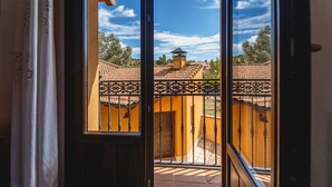 A view through a window with a metal railing, a tiled roof, and a door.