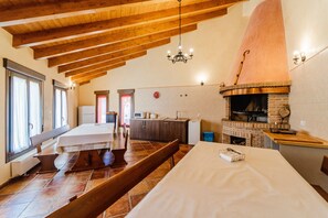 Une salle à manger spacieuse avec un haut plafond en bois et une cheminée en briques.