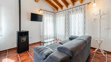 Una sala de estar moderna con un sofá, televisor, chimenea y perchero.