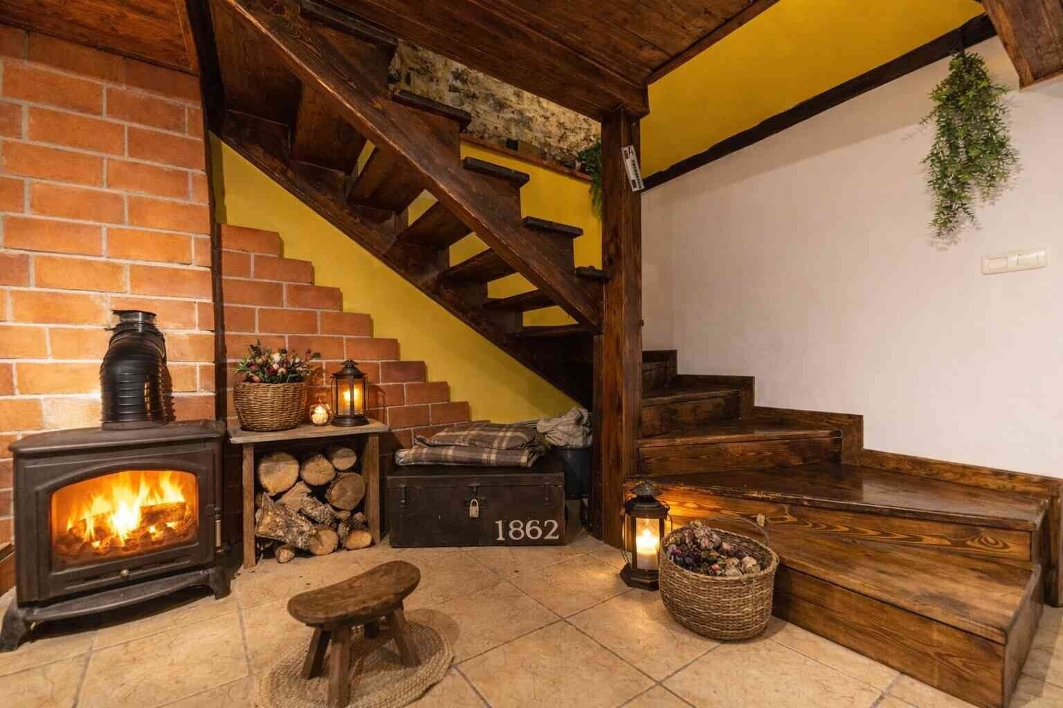 Une pièce chaleureuse avec une cheminée, un escalier en bois et un banc.