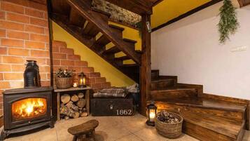 Une pièce chaleureuse avec une cheminée, un escalier en bois et un banc.