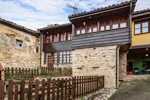 A traditional stone building with wooden balconies and a wooden fence.