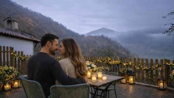 Una pareja sentada a una mesa con velas, con vistas a un paisaje montañoso.