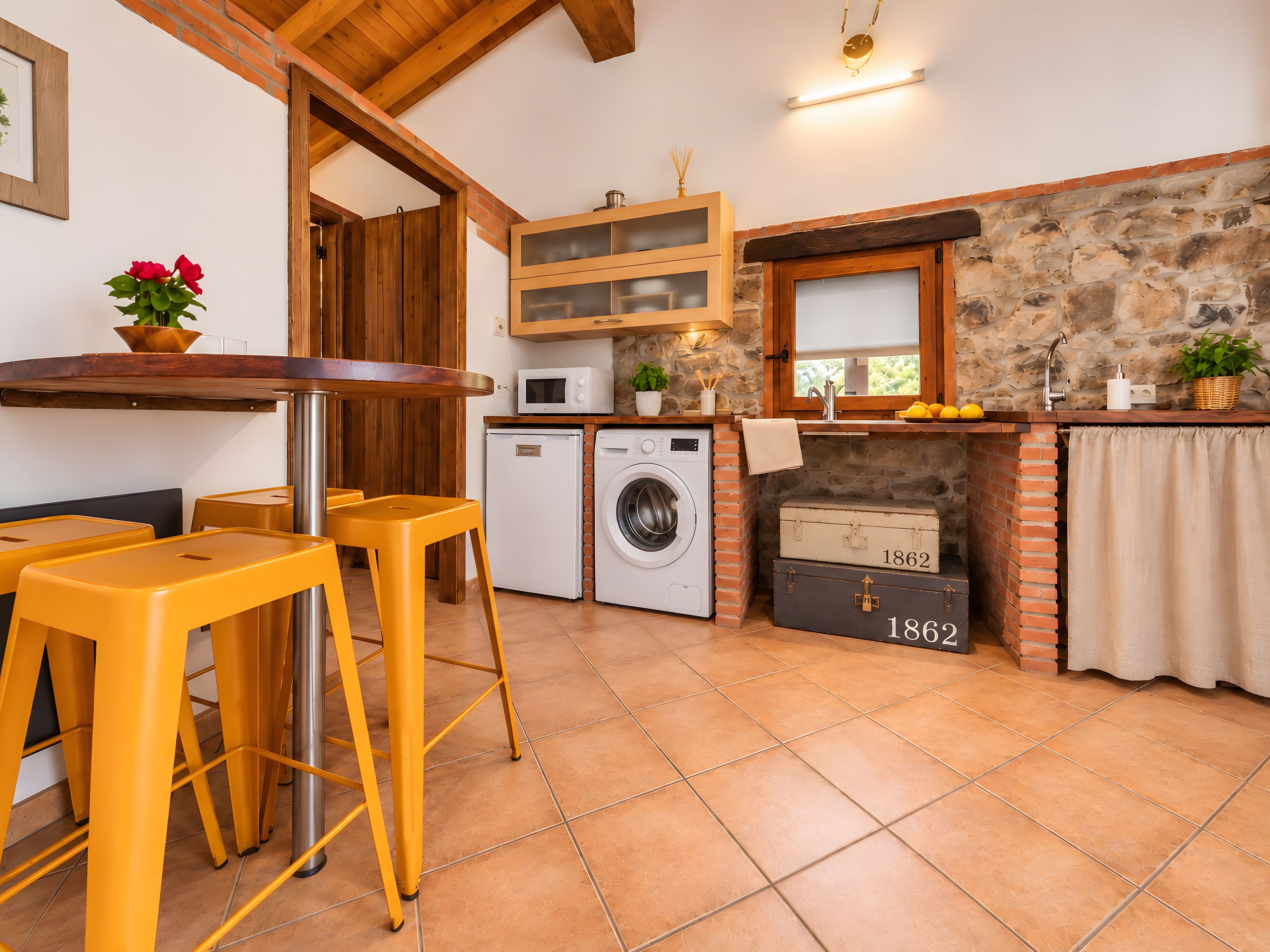Une cuisine compacte équipée d’un lave-linge, d’un four à micro-ondes et d’un mur en pierre.
