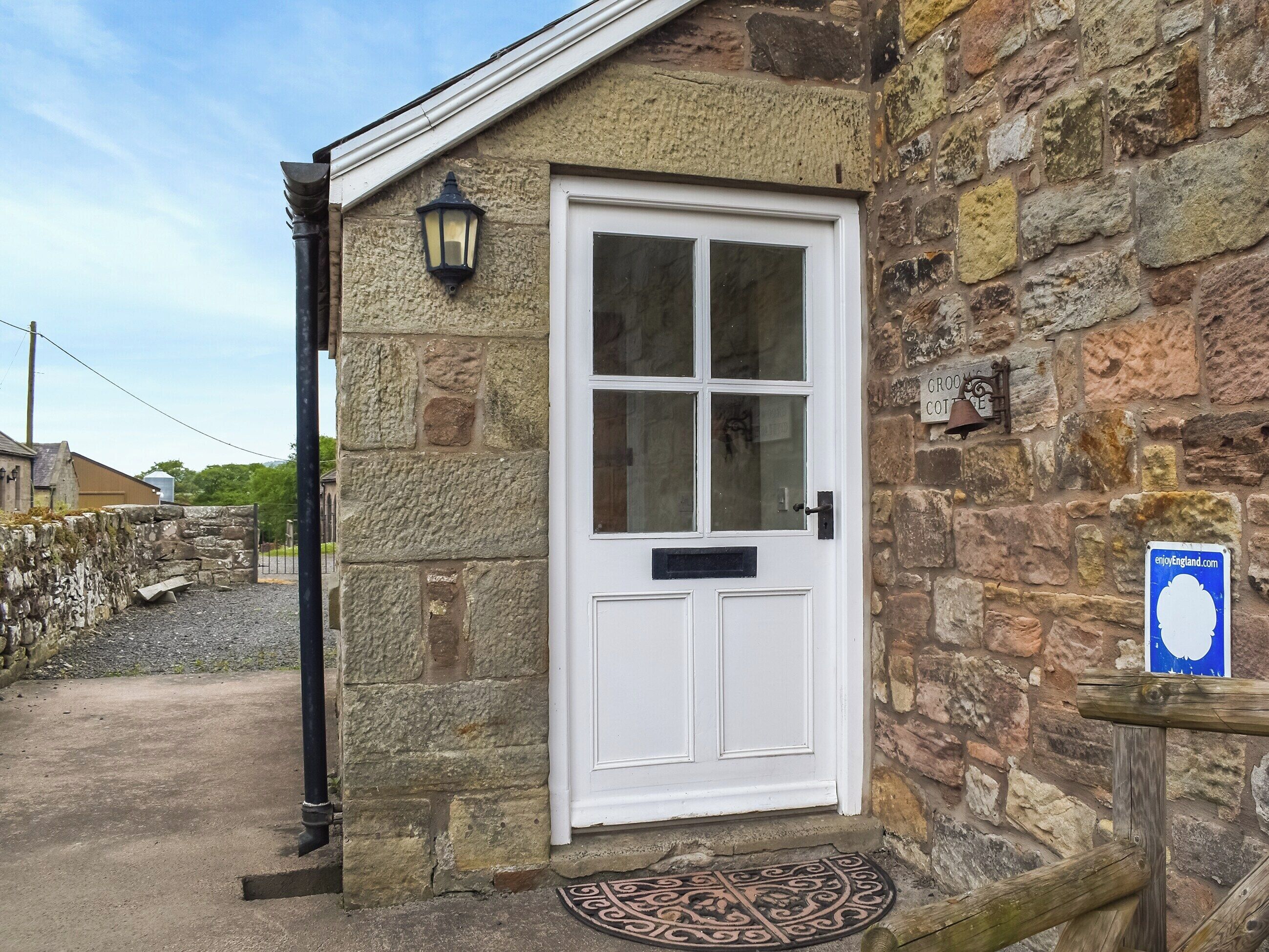A stone building with a white door, a black lantern, and a sign on the wall.