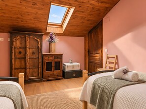 A bedroom with a skylight, wooden wardrobe, and a bed with a rolled towel.