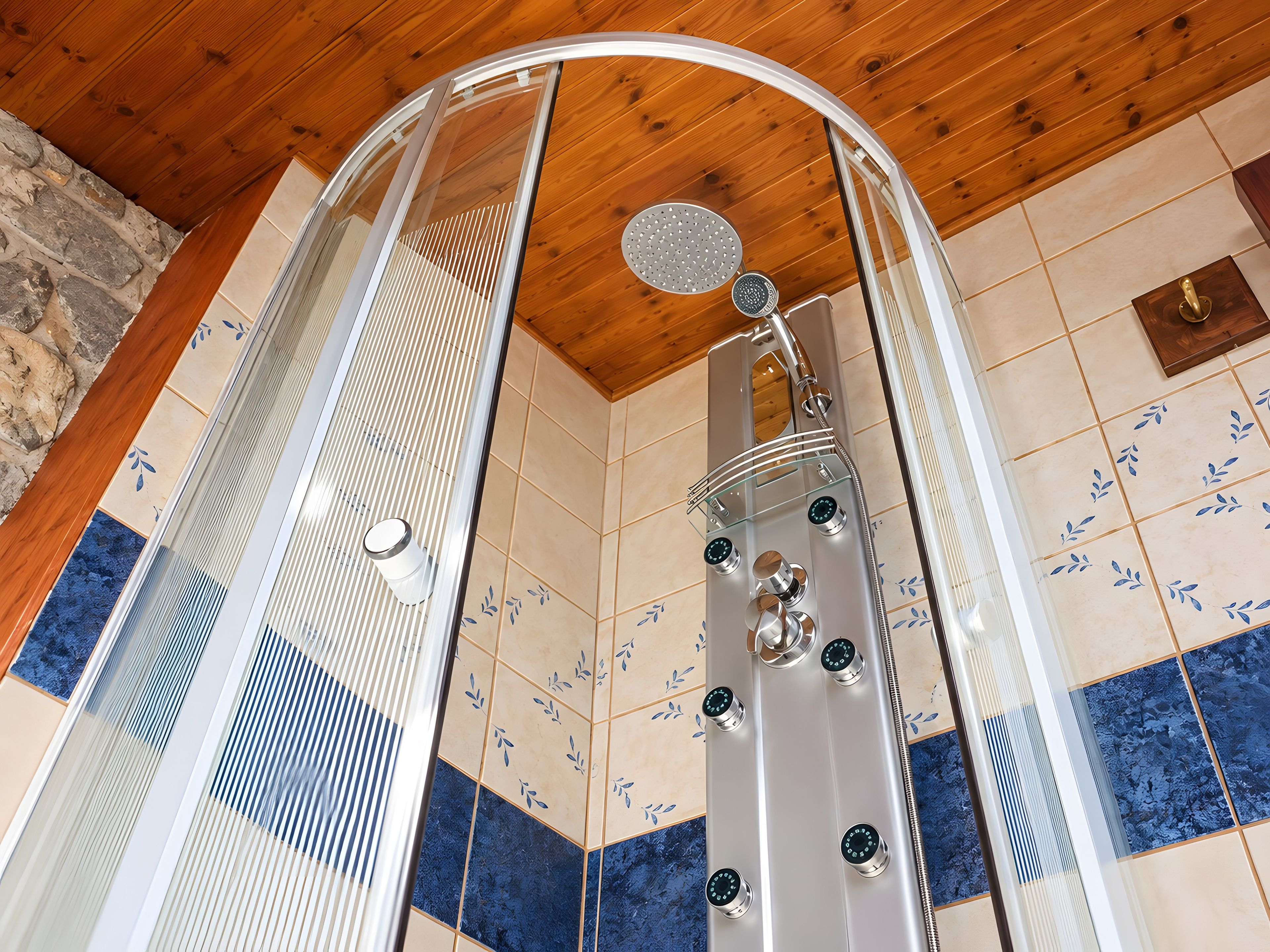 Une cabine de douche dotée d’une porte en verre, d’un pommeau de douche à effet pluie et de plusieurs boutons de commande.