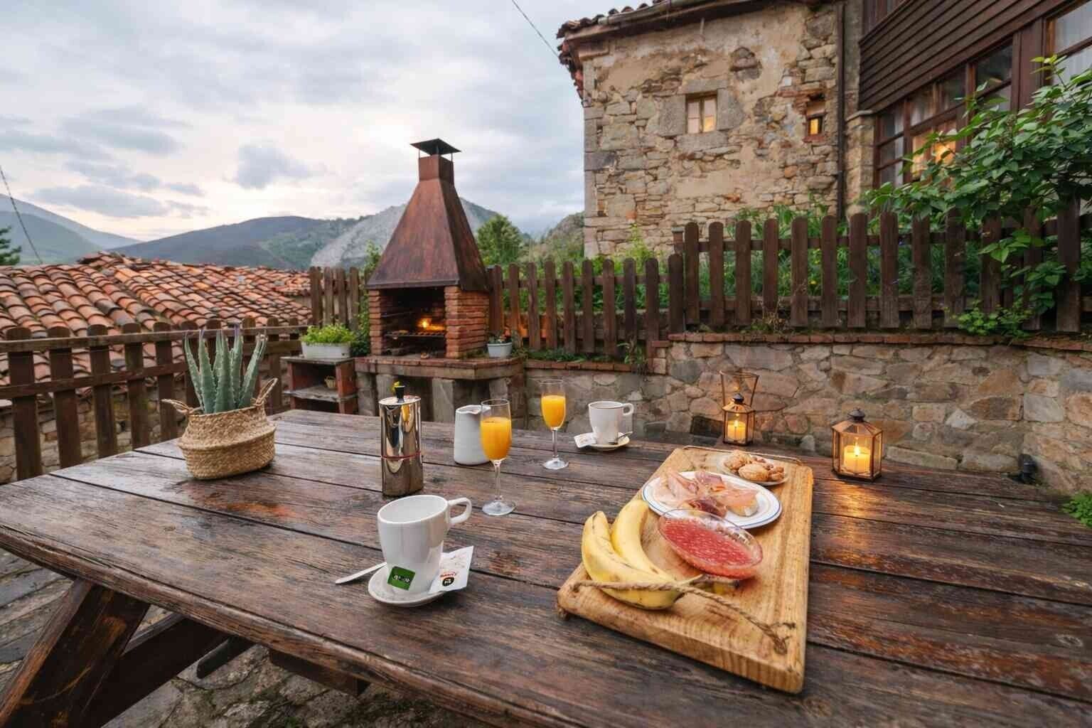 Un'area pranzo esterna rustica con un edificio in pietra, una recinzione in legno e un forno a mattoni.