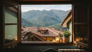 A room with a large window overlooking a mountainous landscape, a wooden ceiling, and a small table with candles. - Montegrande Apartment Surrounded by Mountains with Shared Terrace and Wi-Fi (La Villa de Sub)