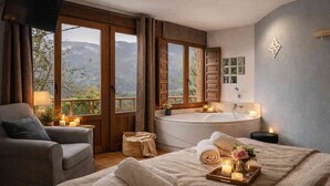 A bedroom with a large bed, a sitting area, a bathtub, and a view of mountains. - Apartment 'El Ablanu, Hot Tub & Mountain Views' with Terrace and Wi-Fi (Proaza)