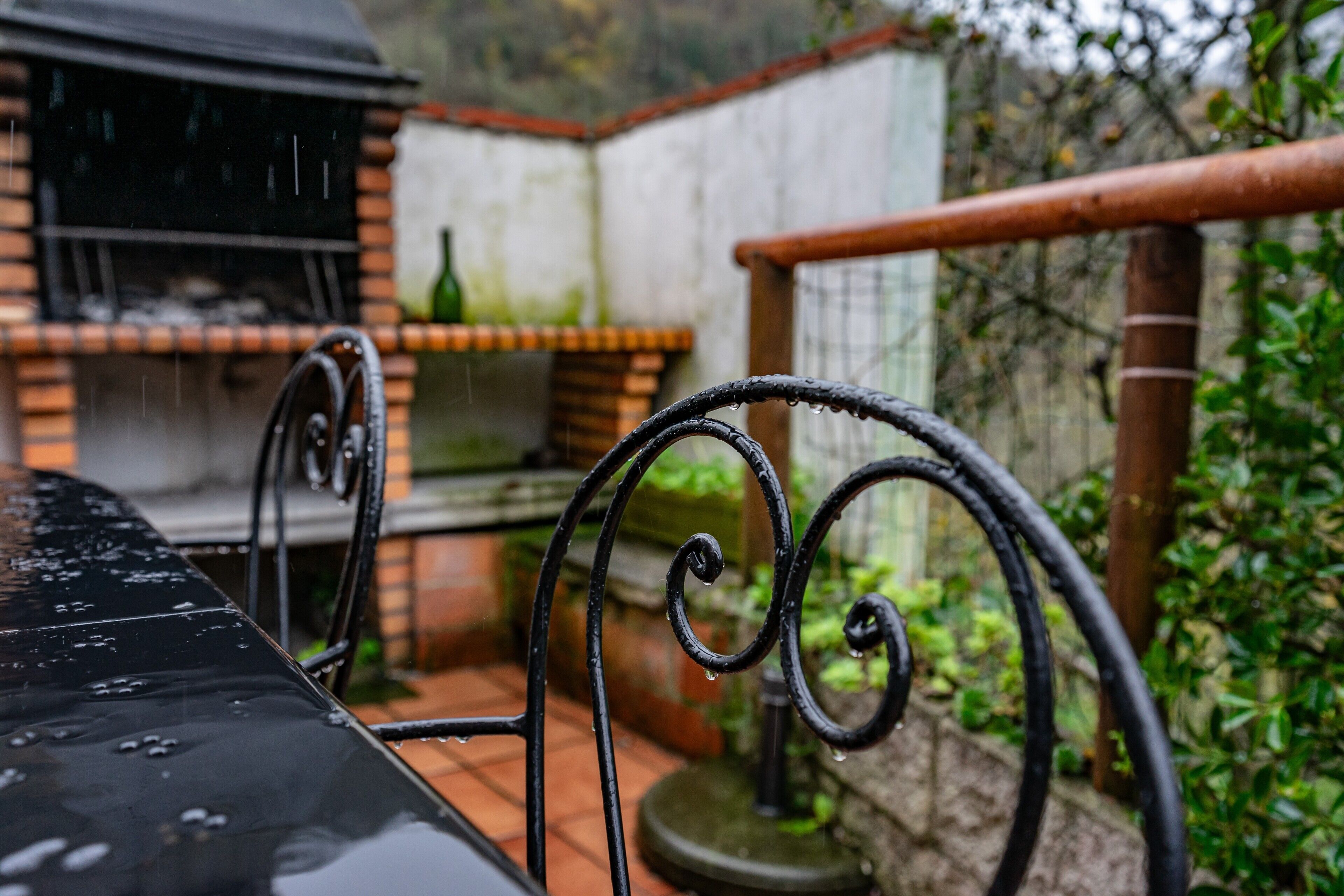 Un patio con una parrilla, baranda metálica y suelo de baldosas.