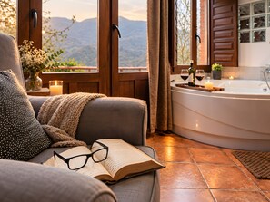 A cozy room with a large window, a bathtub, and a book on a couch. - Apartment 'El Ablanu, Hot Tub & Mountain Views' with Terrace and Wi-Fi (Proaza)