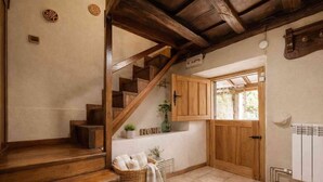 Una escalera de madera conduce a un rellano con un cartel que dice 'HOME', una cesta de mimbre con toallas y un radiador en la pared.