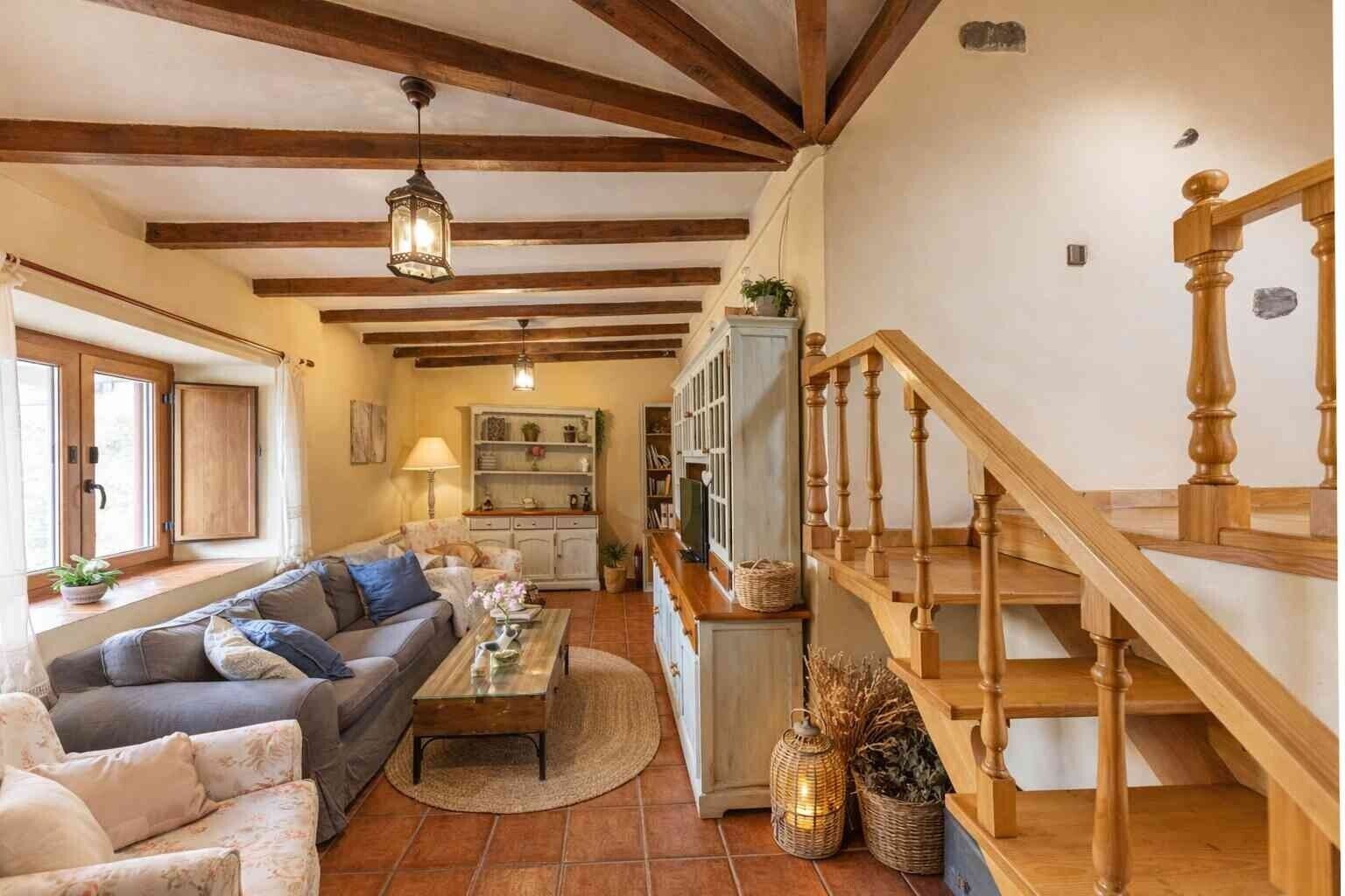 A living room with a sofa, coffee table, and a staircase with wooden railings.