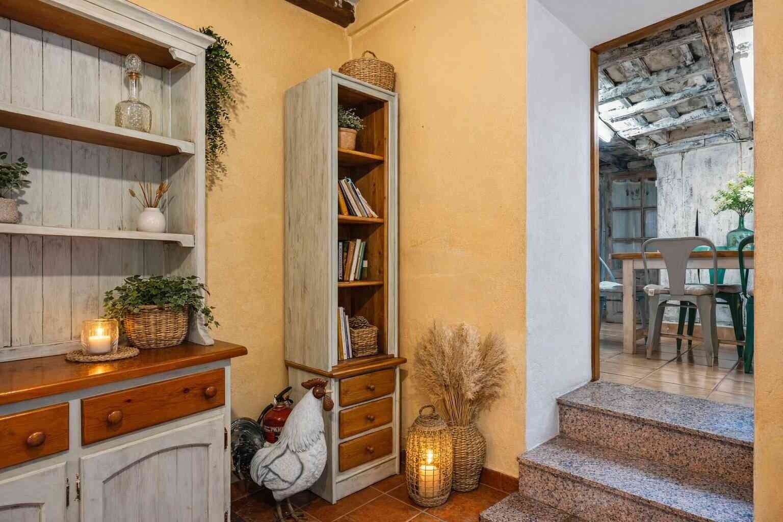 A cozy interior with wooden shelves, a bookshelf, and a staircase leading to another room.