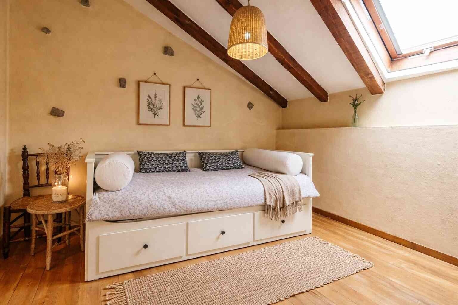 A cozy room with a sofa, a small table with a candle, and framed botanical prints on the wall.