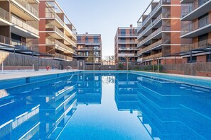 Una piscina rodeada de edificios residenciales de varios pisos con balcones.