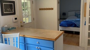 A compact kitchen with blue cabinets, a wooden countertop, and a white dining table.