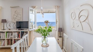 A room with a TV, bookshelves, a vase with flowers, and artwork on the walls.