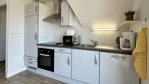 Una cocina moderna con armarios blancos, horno empotrado, microondas, tostadora y cafetera.