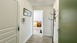 Un pasillo con un perchero, una puerta con manija y un cuadro en la pared.