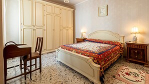 Ein Schlafzimmer mit Bett, Schreibtisch, Stuhl, Kleiderschrank und einer Deckenleuchte.