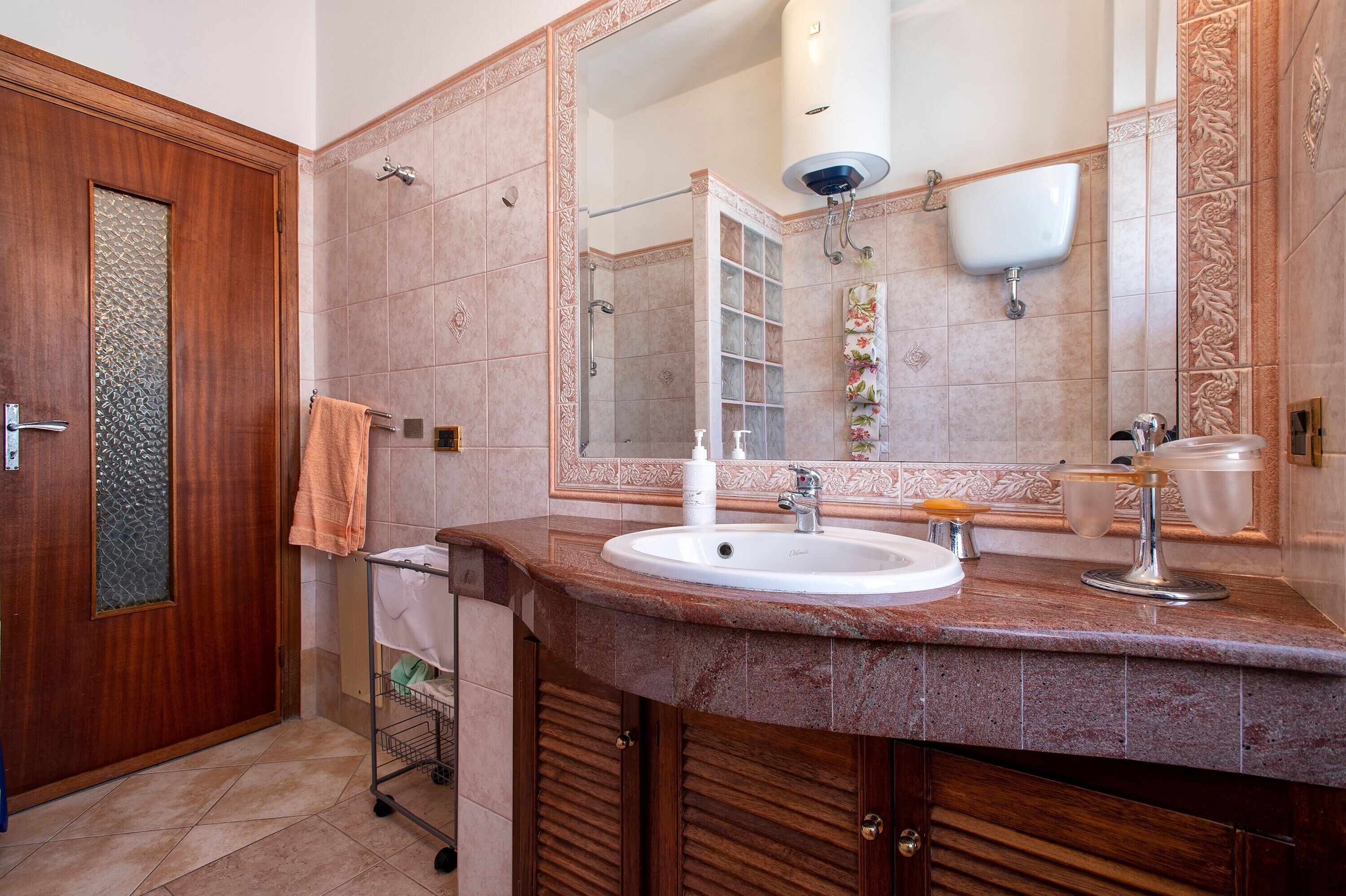 Une salle de bain avec une porte en bois, un grand miroir, un lavabo avec un robinet et un porte-serviettes.