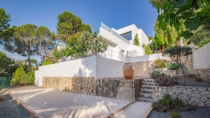 A modern house with a stone wall, a wooden deck, and a large window.