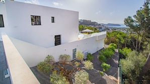 A modern white building with multiple windows and a view of a coastal landscape.