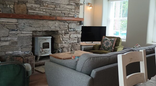 Una sala de estar acogedora con una pared de piedra, una chimenea, un televisor y una zona de estar cómoda.