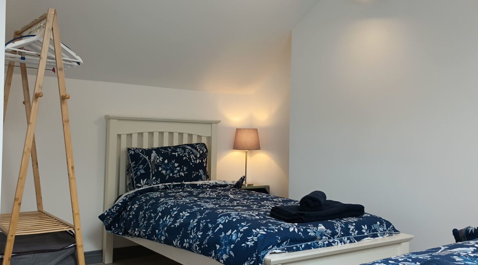 Une chambre à coucher avec un lit, une échelle en bois, une lampe et une table de chevet.
