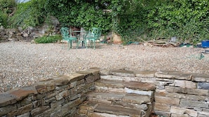 A stone wall with steps leading up to a gravel area.